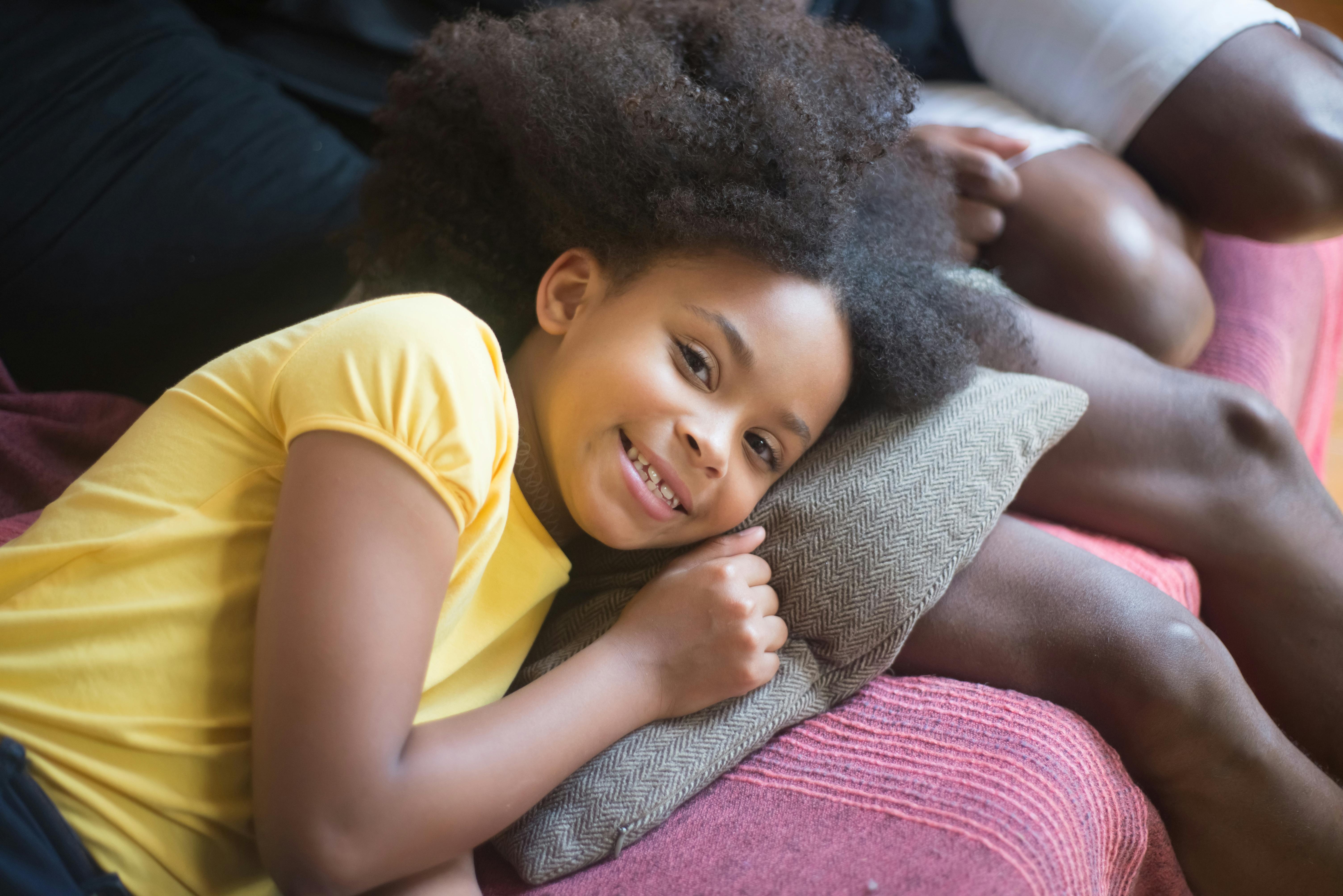a young girl smiling while lying on the sofa
