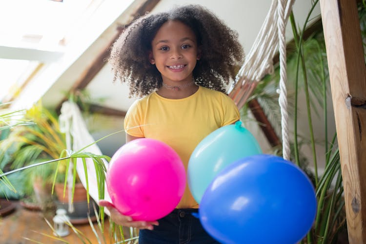 Girl In A Yellow Shirt Holding Colorful Balloons