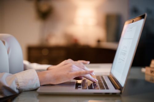 Free Close-up of hands typing on a laptop at home, showcasing a cozy work environment. Stock Photo