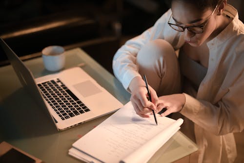 A Woman Sitting at the Table with a Laptop and Documents