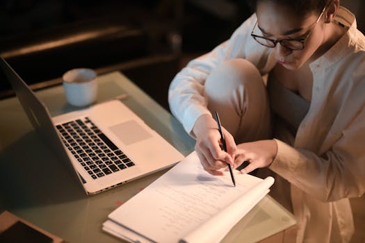 Focused woman taking notes at night while working at home. Cozy and productive ambiance.
