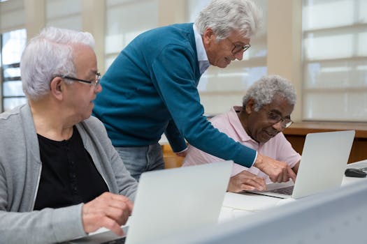 Three senior adults collaborating in a classroom setting on laptops, focusing on technology learning.