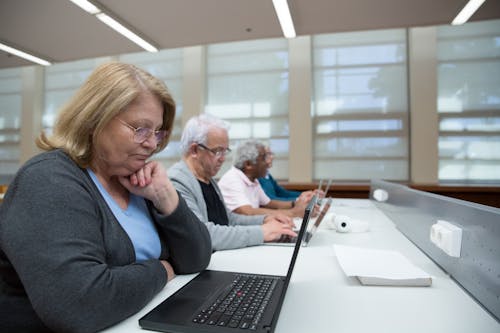 Elderly People Sitting in a Classroom Learning to Use Computers