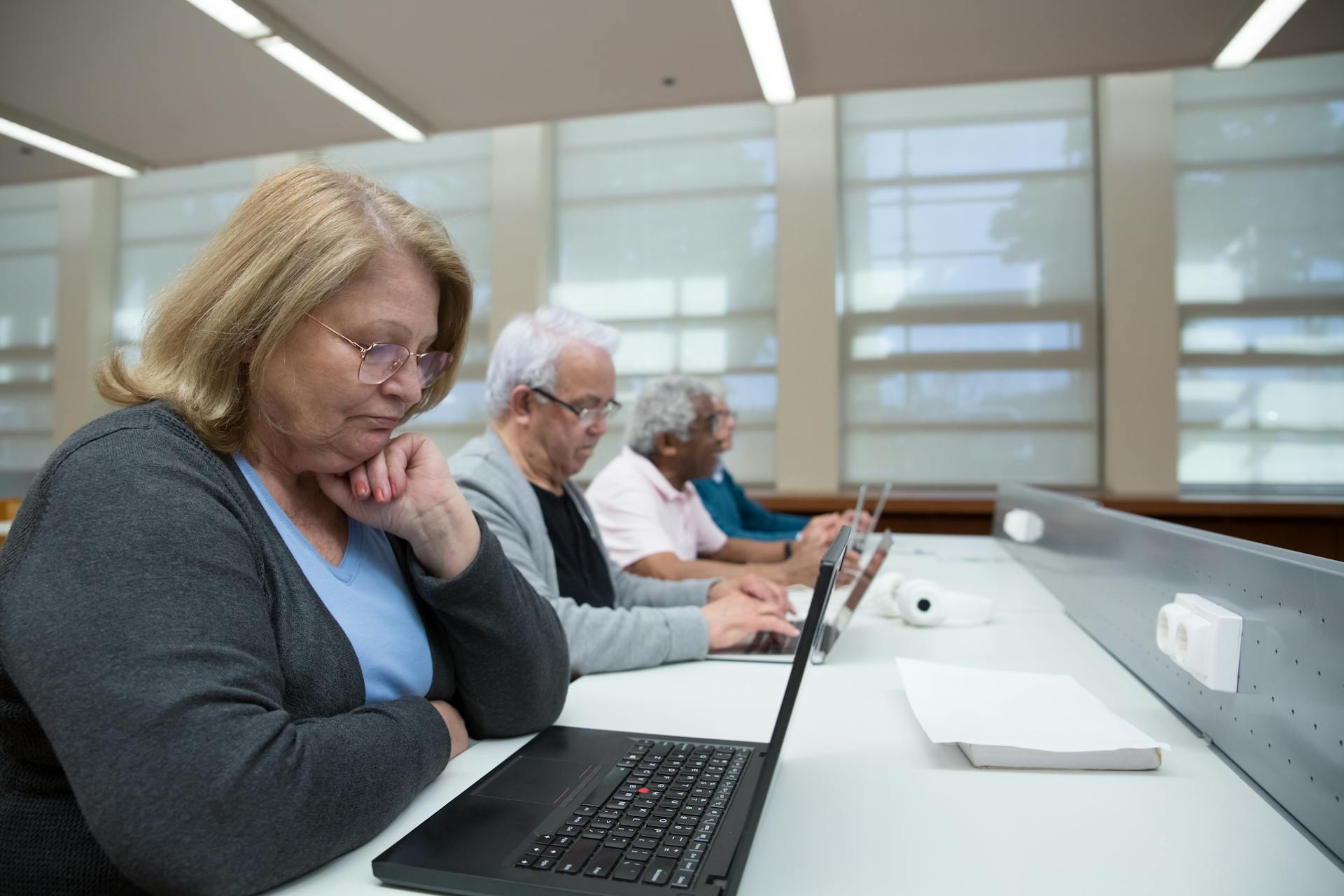 Elderly People Sitting in a Classroom Learning to Use Computers