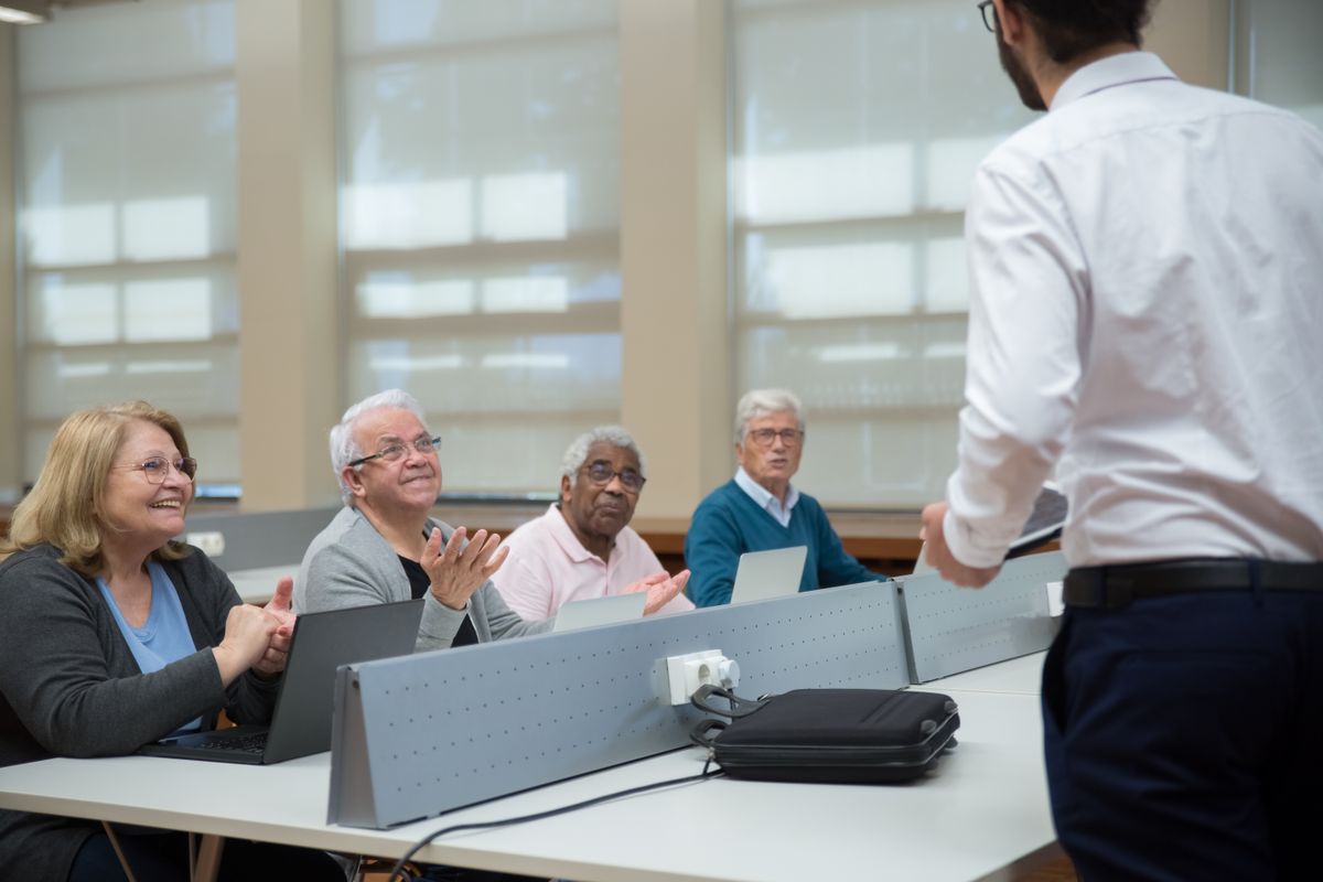 Un groupe d'adultes demandeurs d'emploi en formation collective face à un formateur debout dans une salle