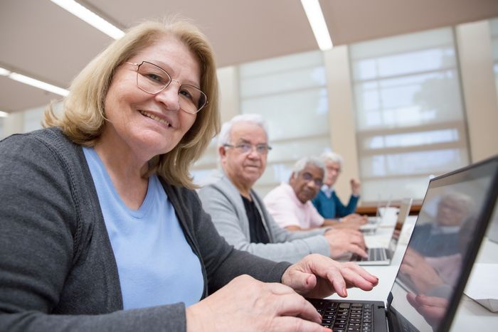 Grupo de adultos mayores aprendiendo a usar computadoras en clase