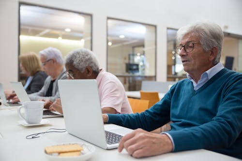 Group of Elderly People Sitting in a Classroom with Laptops 