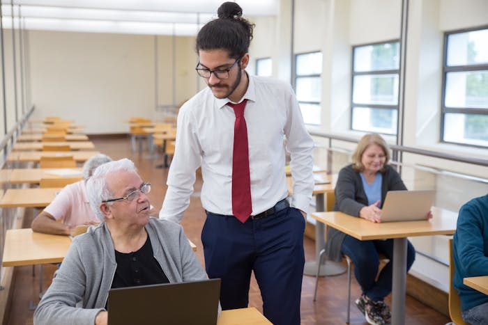 Professor ensinando pessoas mais velhas a usar o computador em ambiente acolhedor