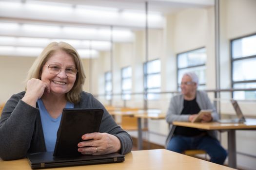 Senior adults in a modern setting engaging with digital devices for learning.