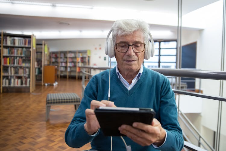 A Man Listening On A Headphone Using A Tablet Computer