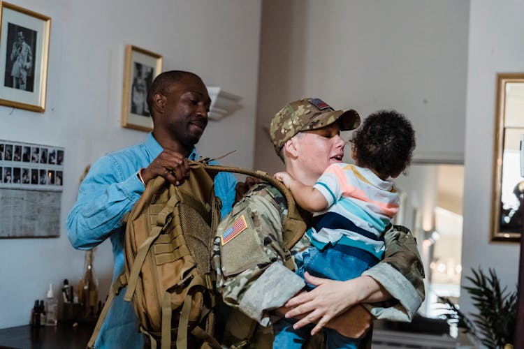 Female Soldier Saying Goodbye To Her Son Putting On Her Backpack 