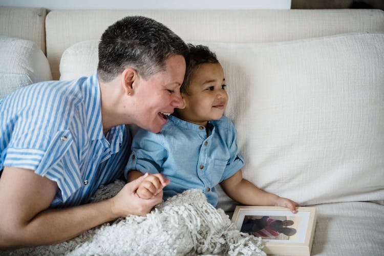 Woman On Sofa With Her Son Showing The Photo Of Soldier Dad