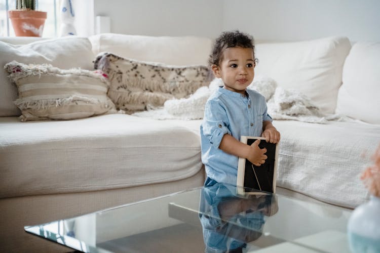 A Cute Child Holding A Picture Frame