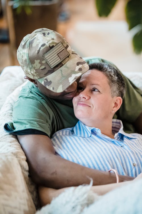 Man in Military Uniform Sitting on a Sofa and Embracing his Wife 