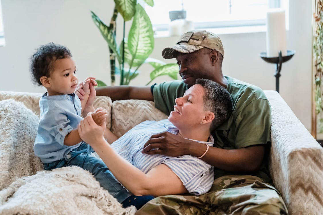 Free Man Embracing his Wife and Playing with Their Child on the Sofa Stock Photo