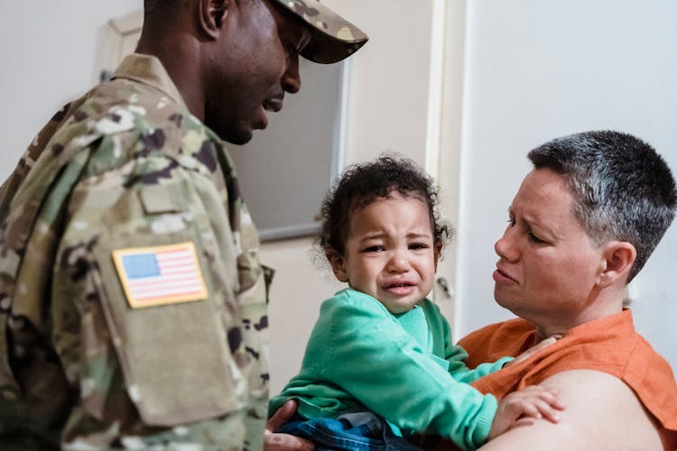 Man Standing By A Woman Holding Their Crying Son