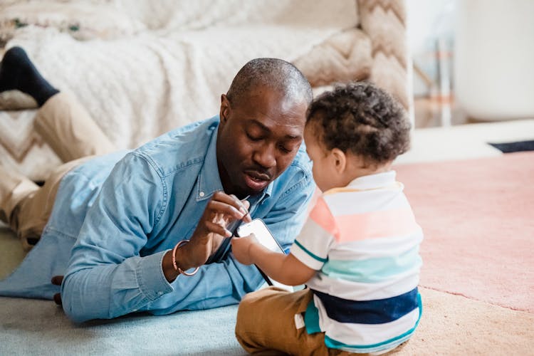 Father Teaching Toddler How To Use Phone