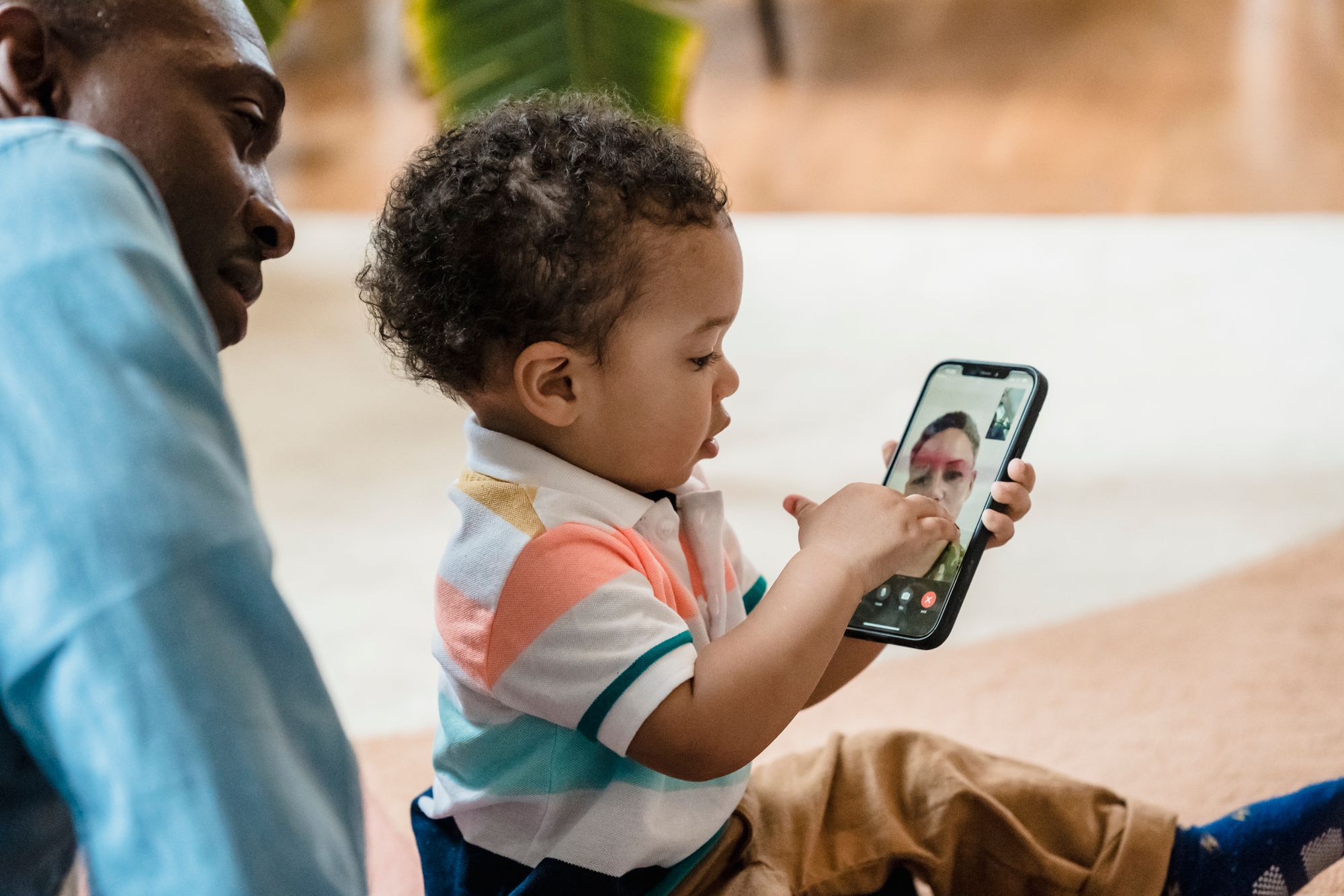A child using a smartphone for a video call, learning technology skills indoors.