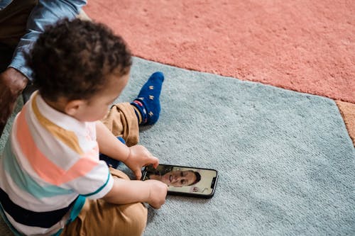 A Child Sitting on the Floor with a Phone