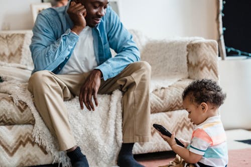 Man Looking at his Son Playing on a Phone