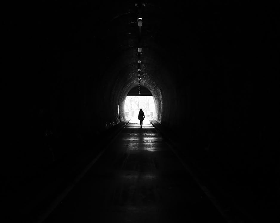 Silhouette of a Person Walking Inside a Tunnel