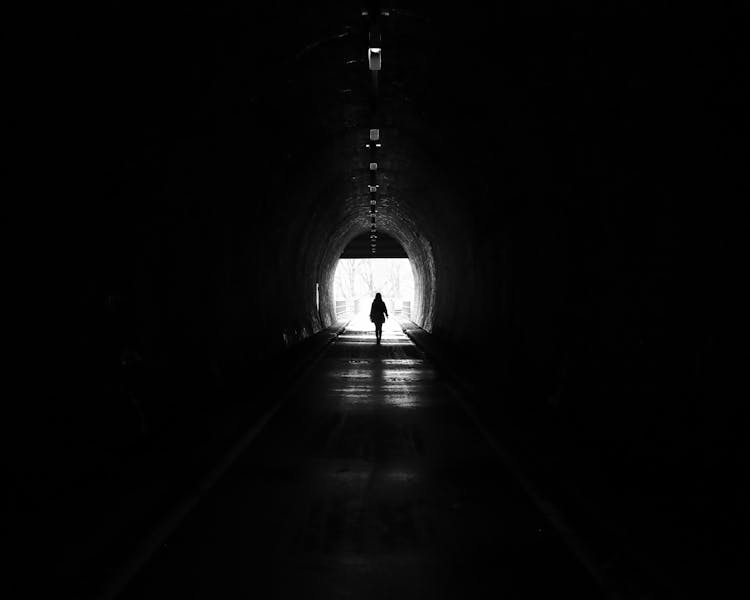 Silhouette Of A Person Walking Inside A Tunnel