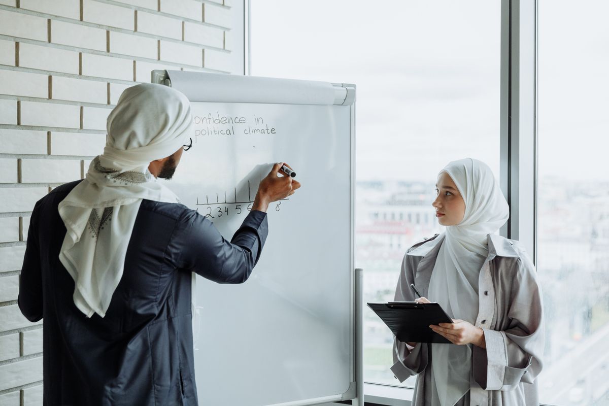 Two people writing a project plan on a whiteboard