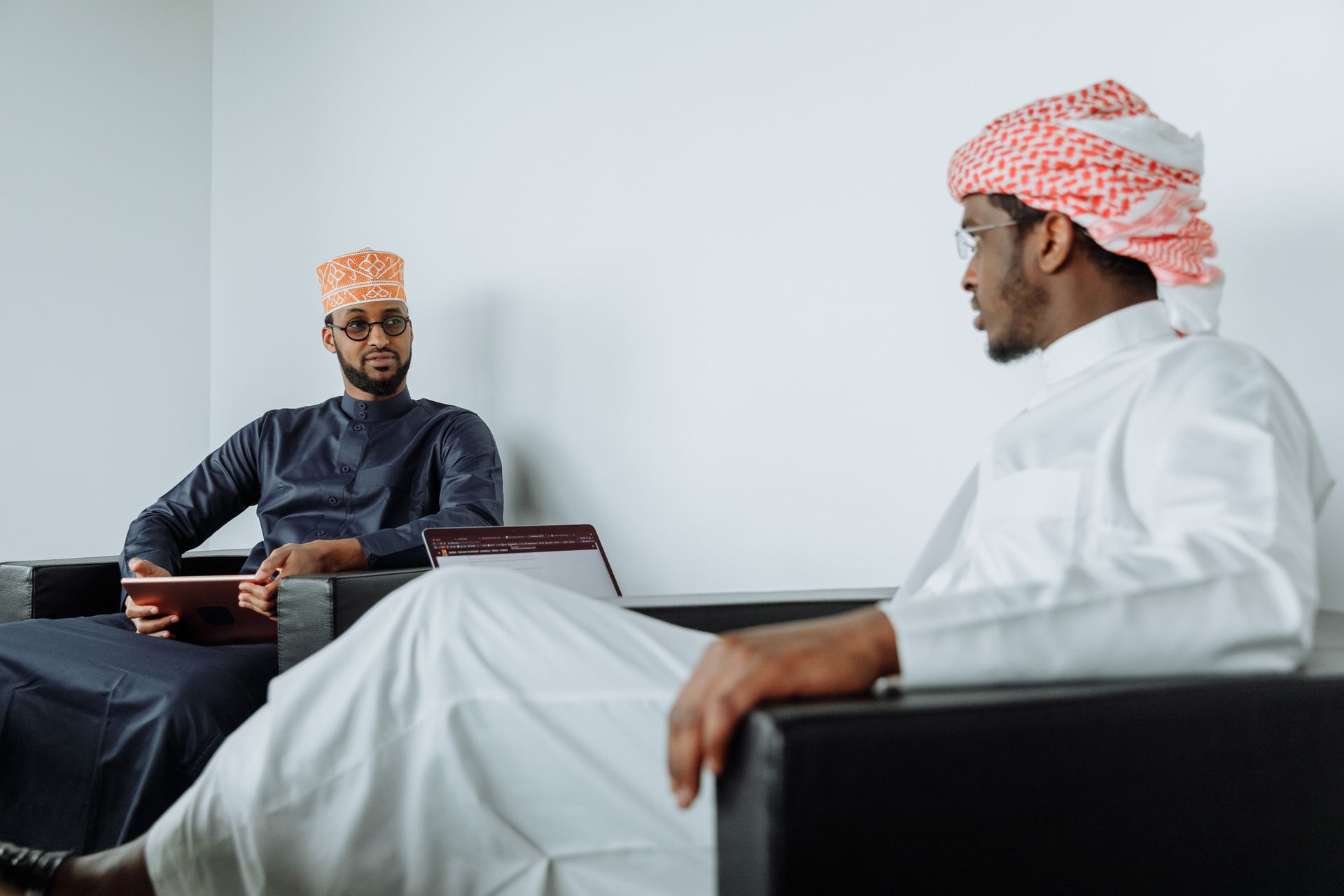 Two Middle Eastern businessmen in traditional attire having a professional meeting indoors.