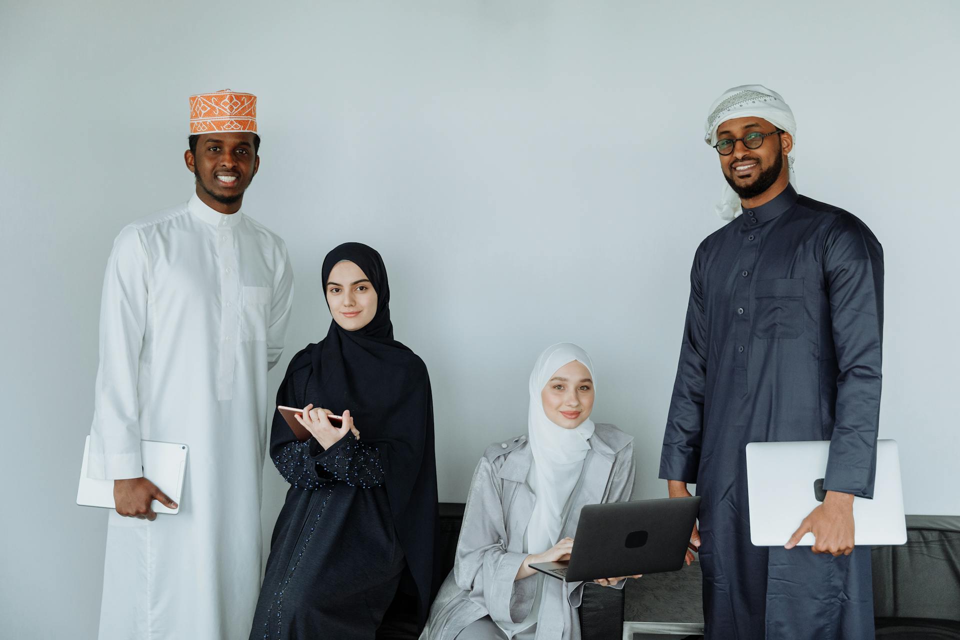 A diverse team of Muslim colleagues working indoors, showcasing modern technology and traditional attire.