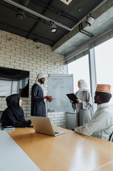 Professionals in traditional attire discussing strategies at a modern office meeting.