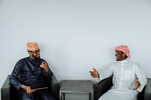 Free Two men in traditional clothing engaging in a friendly discussion indoors. Stock Photo