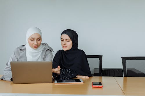 Free Two Women Wearing Hijabs Using Laptop and Discussing Stock Photo