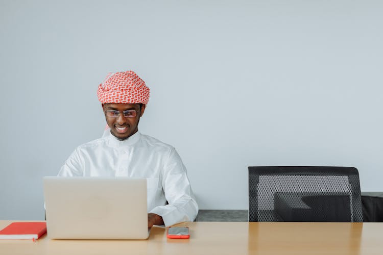 Man In White Thobe Using A Laptop