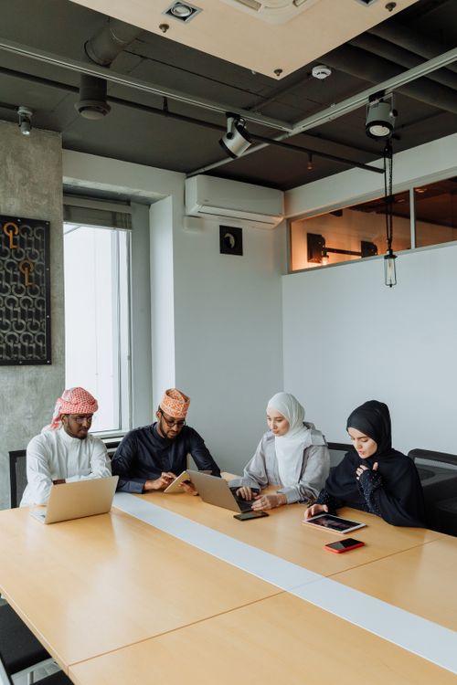 Free A group of Muslim professionals collaborating in a modern meeting room with laptops and tablets. Stock Photo