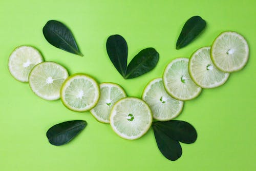 Free Close-Up Shot of Slices of Lime on a Green Surface Stock Photo