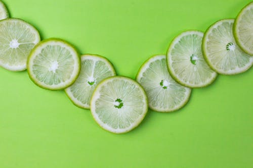 Free Close-Up Shot of Slices of Lime on a Green Surface Stock Photo