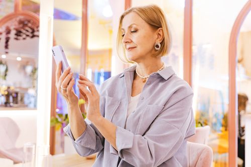 Free Stylish senior woman with short hair using a smartphone in a trendy cafe. Stock Photo