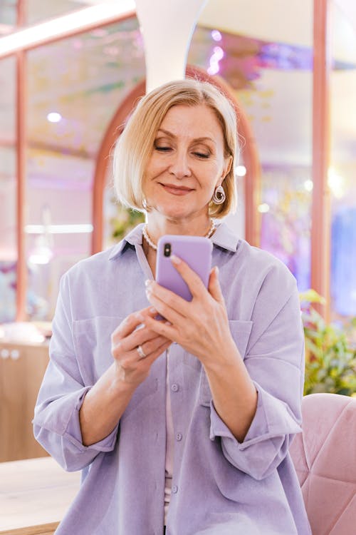 A Portrait of a Mature Woman Smiling while Looking at a Smartphone