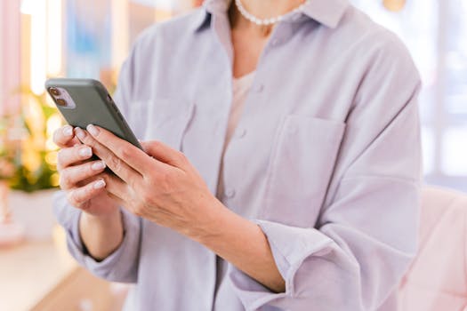 Close-up of a woman using a smartphone inside a bright, modern office space.