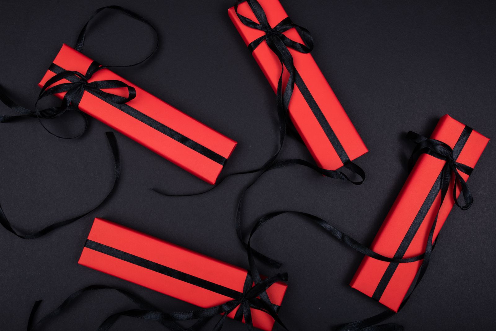 Gift boxes tied with ribbon on a dark surface, photo by Tamanna Rumee on Pexels