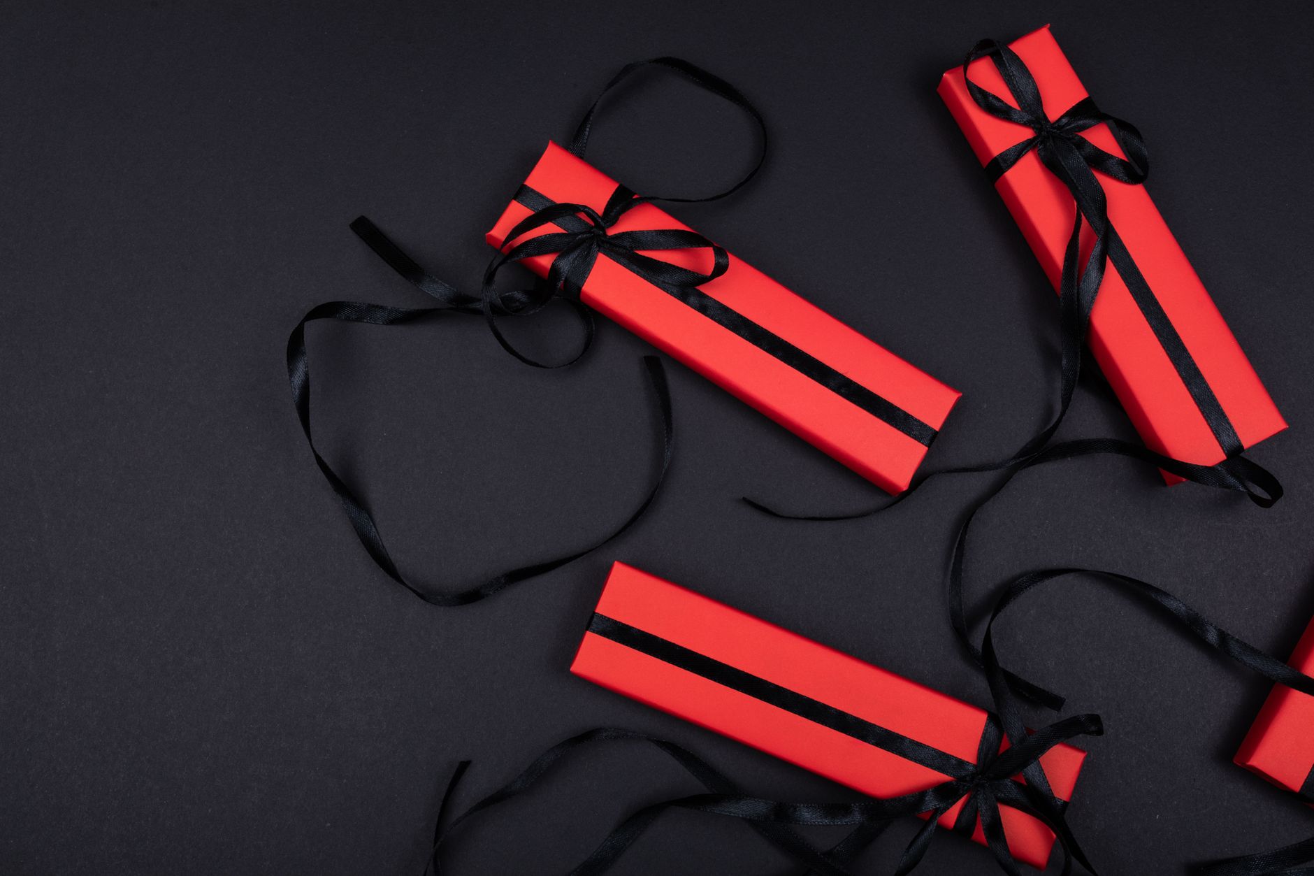 Top view of red gift boxes with black ribbons on a dark background.