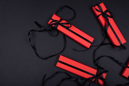 Top view of red gift boxes with black ribbons on a dark background.