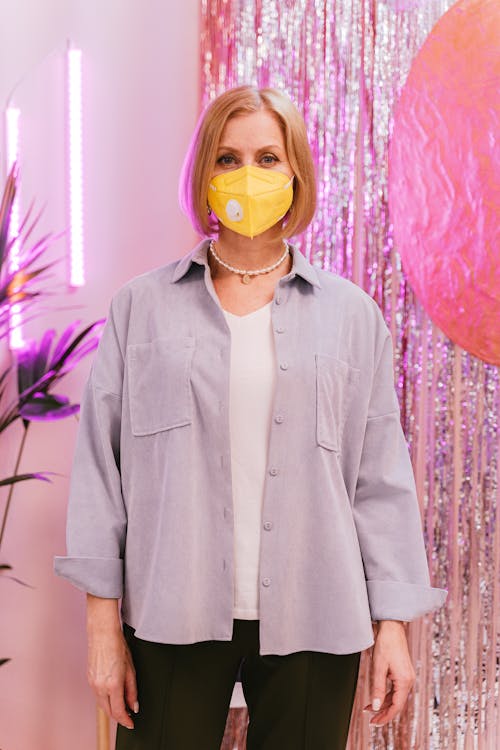 A Woman in Gray Button Up Shirt Wearing Yellow Face Mask