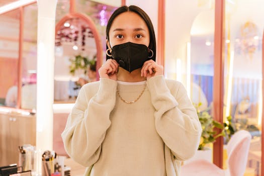 Woman in cozy sweater wearing a face mask indoors, embodying stylish protection.