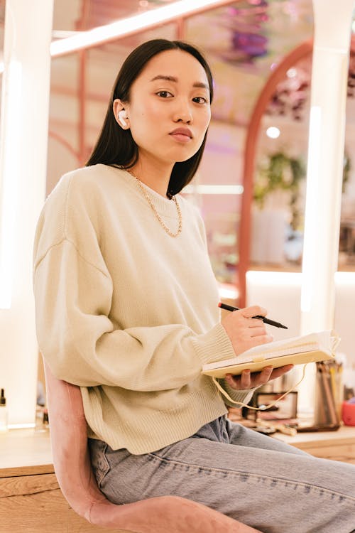 Woman Sitting on Chair Holding Notepad and Pen