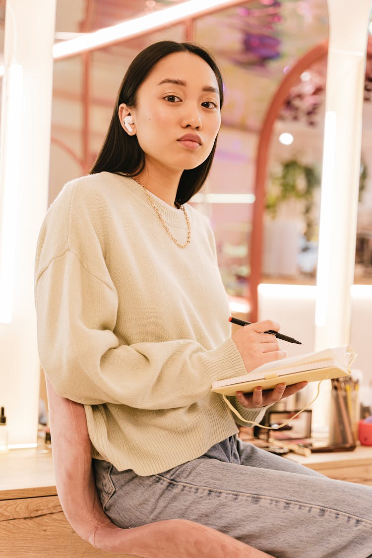 Woman Sitting On Chair Holding Notepad And Pen