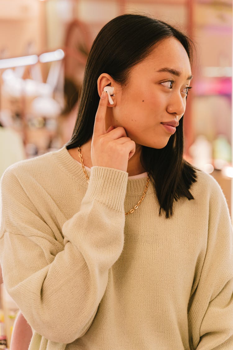 Woman In Beige Sweater Wearing White Earbud