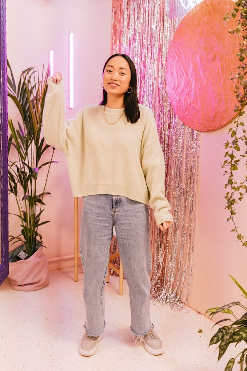 A Woman Wearing Beige Sweater Standing Near the Shimmer Curtain