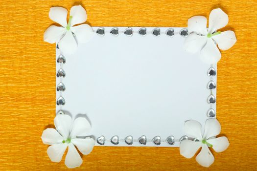 Elegant white jasmine flowers border a blank card on a vibrant orange background.