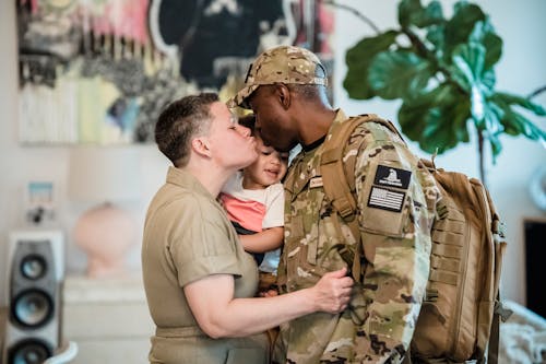 Free A Man in Military Uniform Kissing his Wife and Kid Stock Photo